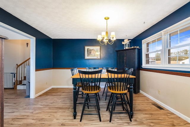 dining space with baseboards, visible vents, stairway, light wood-style floors, and a notable chandelier