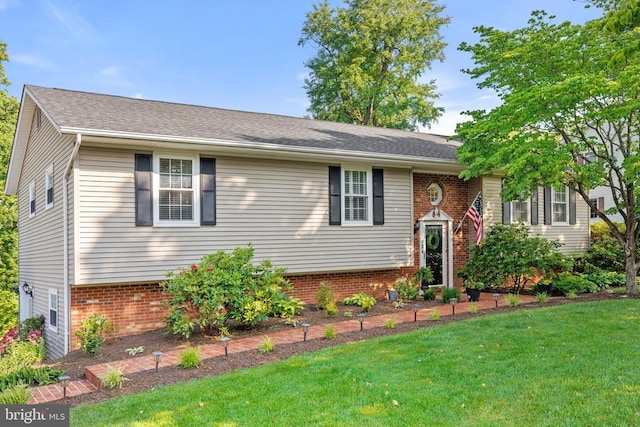 bi-level home with brick siding, a front yard, and a shingled roof