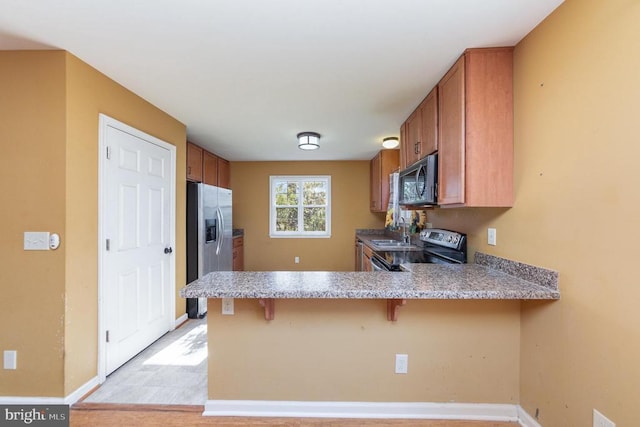 kitchen with stainless steel appliances, a kitchen breakfast bar, kitchen peninsula, and sink