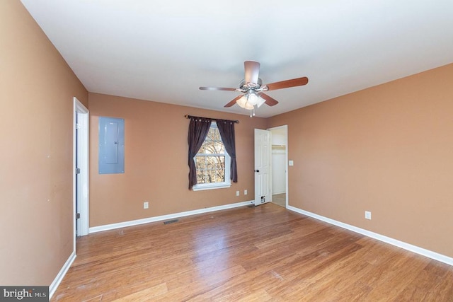 unfurnished room featuring ceiling fan, electric panel, and light wood-type flooring