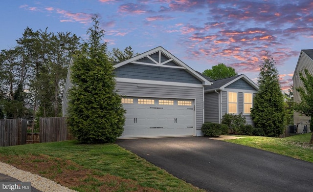 view of front of home with fence, an attached garage, aphalt driveway, central AC unit, and a lawn
