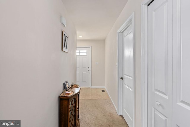 corridor with baseboards and light colored carpet