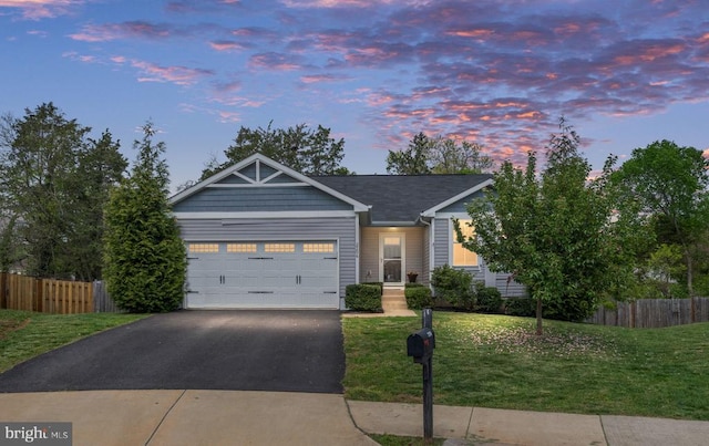 view of front of house featuring fence, an attached garage, a lawn, and aphalt driveway
