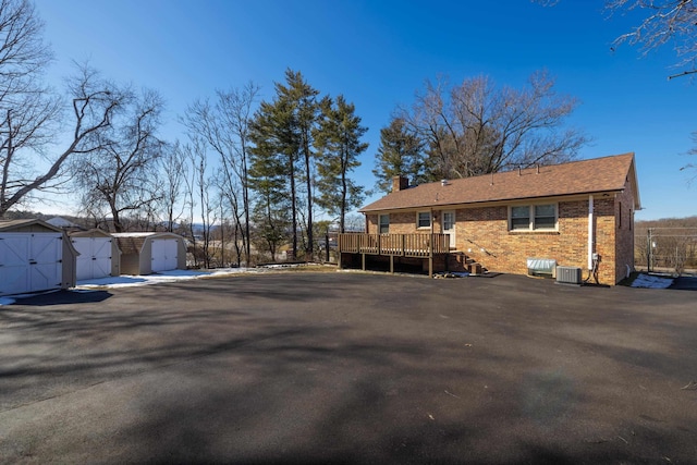 exterior space with central AC unit, a shed, and a wooden deck