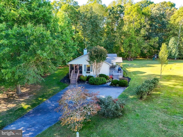 view of front of house featuring a porch, a chimney, aphalt driveway, and a front yard