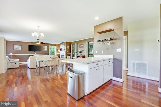 kitchen with visible vents, wood finished floors, a notable chandelier, and a peninsula