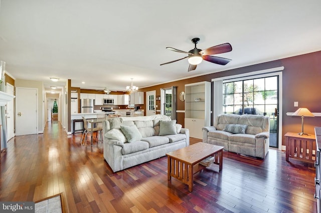 living area featuring dark wood-type flooring, ornamental molding, and ceiling fan with notable chandelier