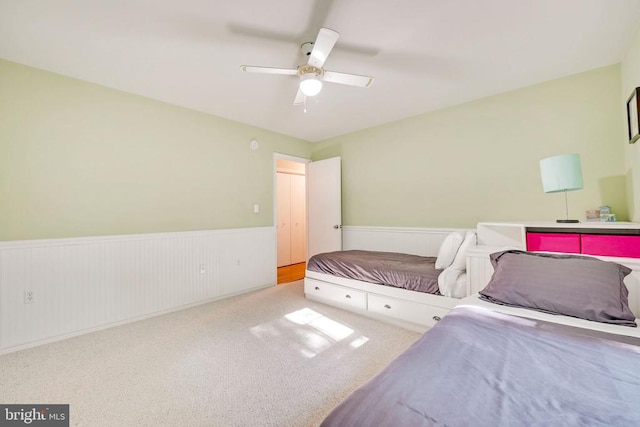 bedroom featuring carpet, a wainscoted wall, and ceiling fan