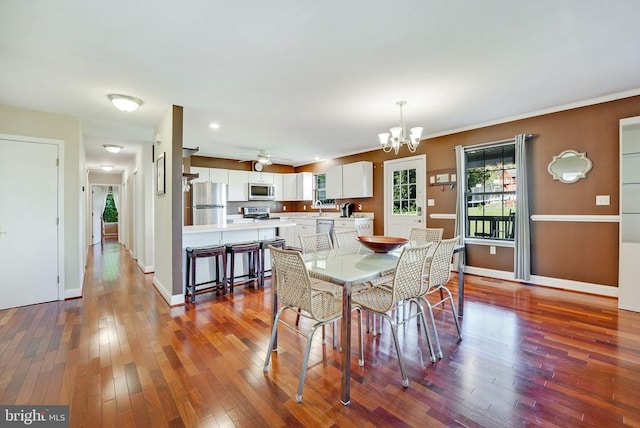 dining space with dark wood-type flooring, baseboards, and ceiling fan with notable chandelier