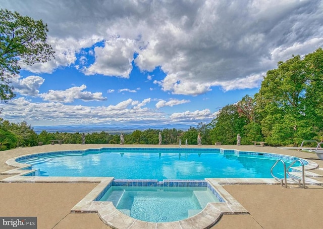 view of swimming pool with a patio and a pool with connected hot tub