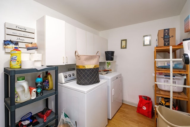 washroom with cabinets, washing machine and dryer, and light hardwood / wood-style flooring