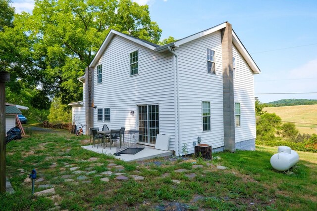 rear view of property featuring a yard, central AC unit, and a patio