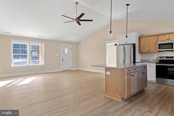 kitchen featuring stainless steel appliances, a center island, light stone counters, white cabinets, and light wood-type flooring