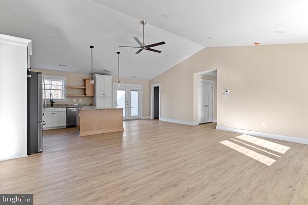 unfurnished living room featuring lofted ceiling, sink, light hardwood / wood-style floors, and ceiling fan