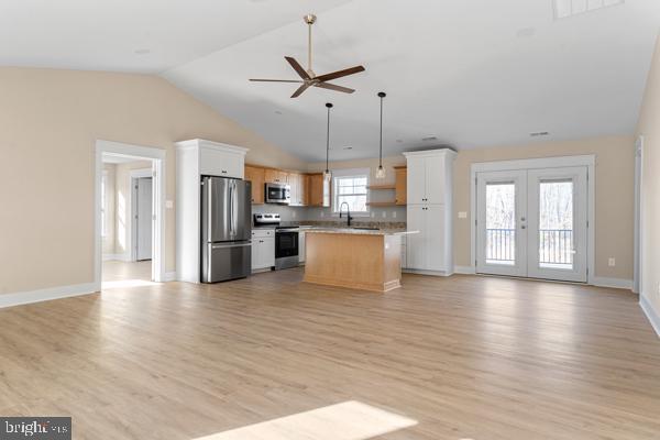 kitchen with appliances with stainless steel finishes, white cabinetry, hanging light fixtures, a center island, and ceiling fan