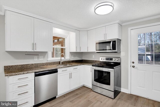 kitchen featuring sink, stainless steel appliances, light hardwood / wood-style floors, and white cabinets