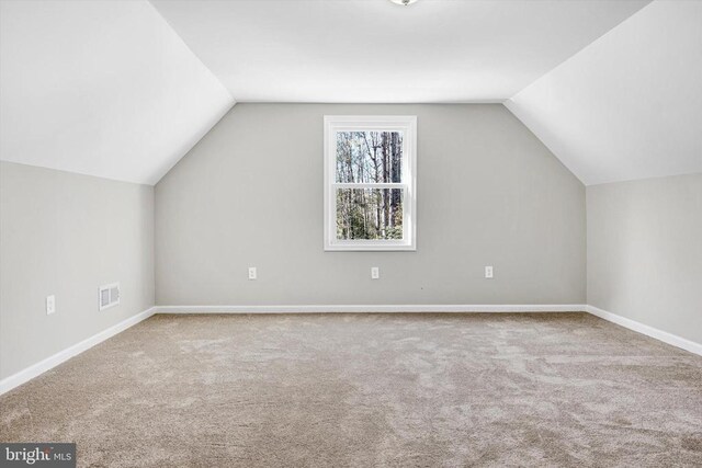 additional living space featuring lofted ceiling and light colored carpet