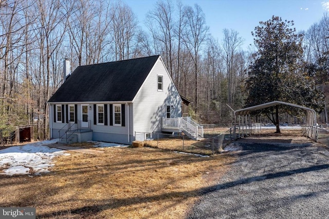 view of side of property with a carport, a chimney, and gravel driveway