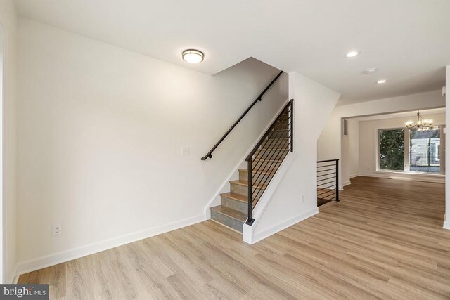 staircase featuring hardwood / wood-style floors and a notable chandelier