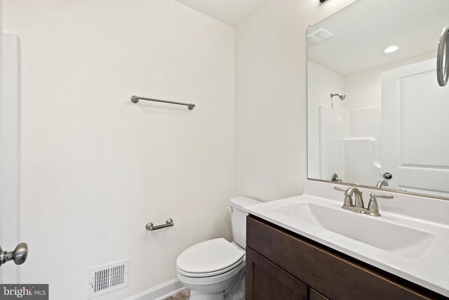 bathroom featuring walk in shower, vanity, and toilet