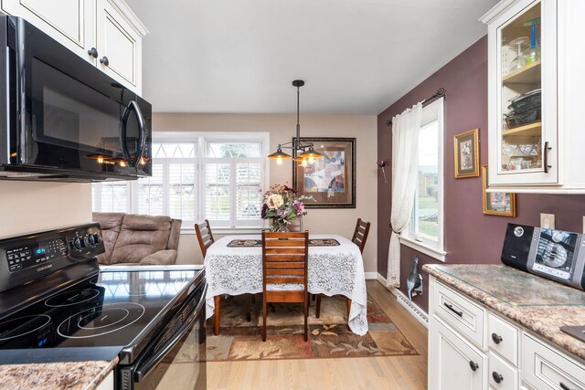 kitchen featuring white cabinetry, light stone countertops, light wood-type flooring, and black appliances