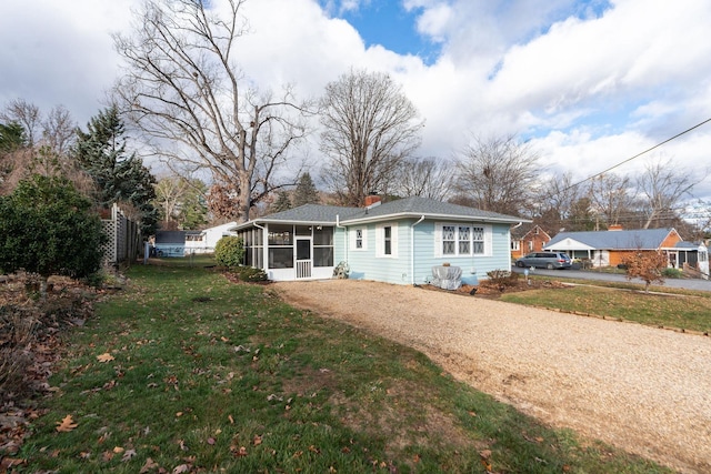 rear view of house featuring a sunroom and a lawn