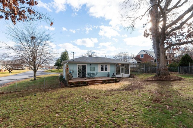 back of house featuring a wooden deck, a yard, and a sunroom