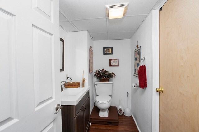 bathroom with vanity, hardwood / wood-style flooring, toilet, and a drop ceiling