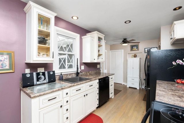 kitchen with sink, black appliances, light hardwood / wood-style flooring, ceiling fan, and white cabinets