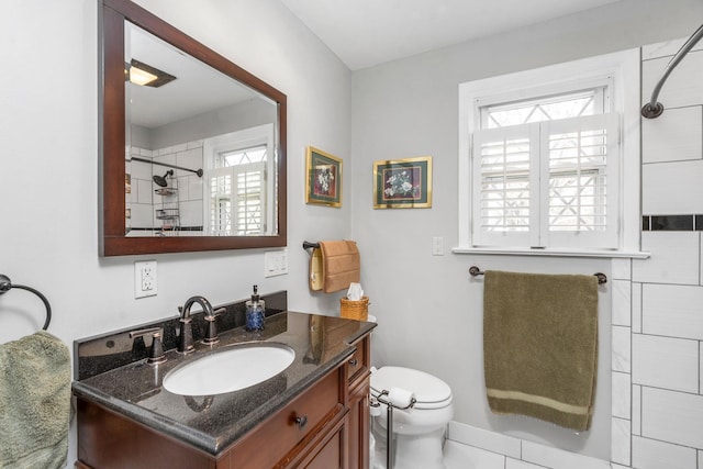 bathroom featuring vanity, tiled shower, and toilet