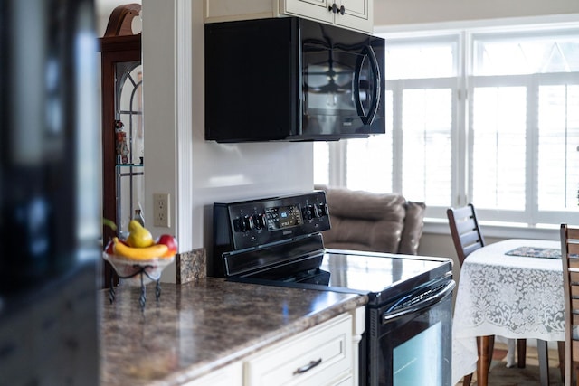 kitchen with white cabinetry, dark stone counters, and black appliances