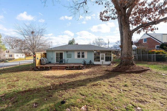 rear view of property featuring a wooden deck, a lawn, and a sunroom