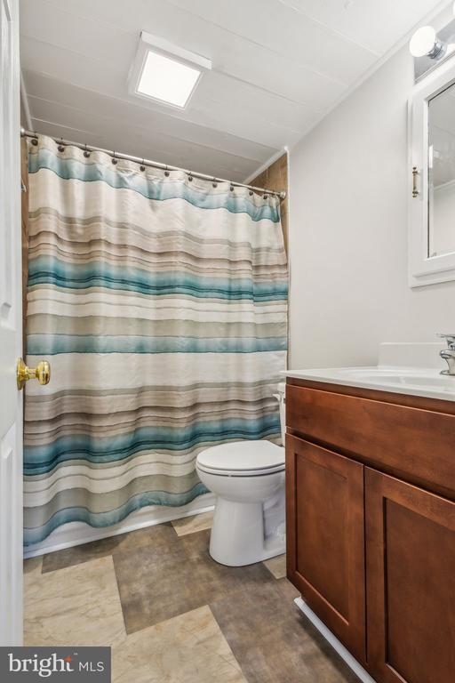 full bathroom featuring vanity, shower / tub combo, and toilet