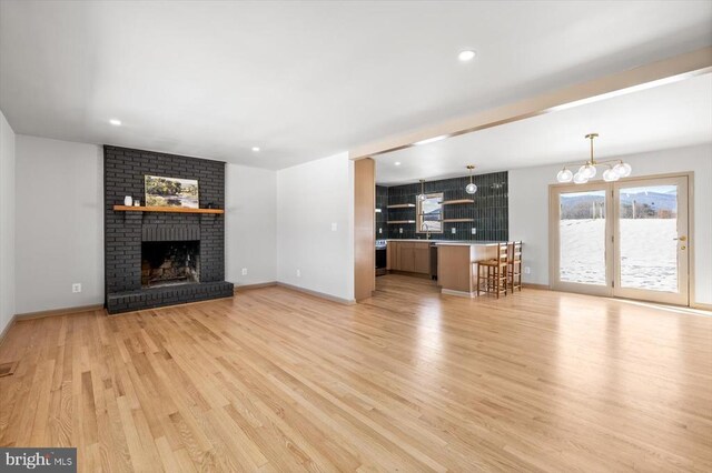 unfurnished living room with a brick fireplace, light hardwood / wood-style flooring, and sink