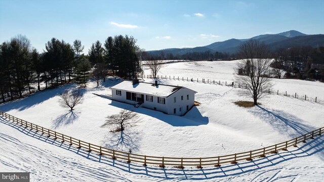 snowy aerial view featuring a rural view and a mountain view