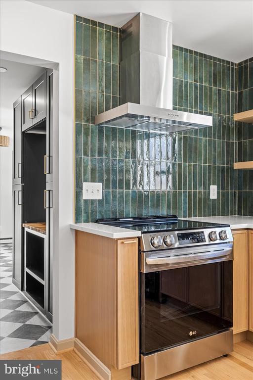 kitchen with stainless steel range with electric stovetop and wall chimney range hood