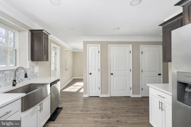 kitchen featuring white cabinetry, sink, stainless steel appliances, crown molding, and dark brown cabinets