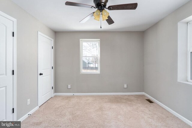 empty room featuring light colored carpet and ceiling fan