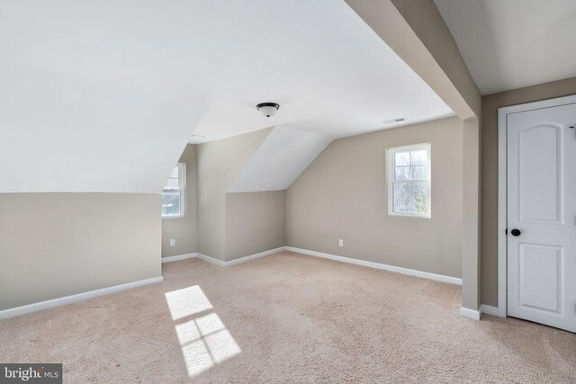 bonus room with light carpet and vaulted ceiling