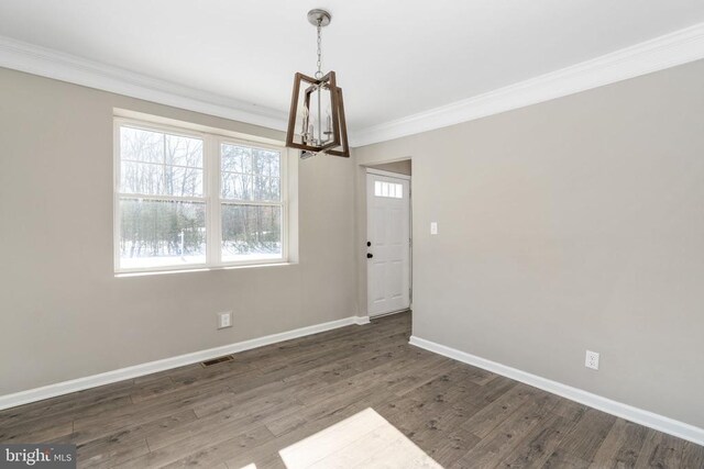 unfurnished dining area with crown molding, dark wood-type flooring, and a notable chandelier