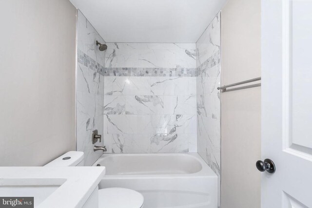 full bathroom featuring vanity, tiled shower / bath combo, and toilet