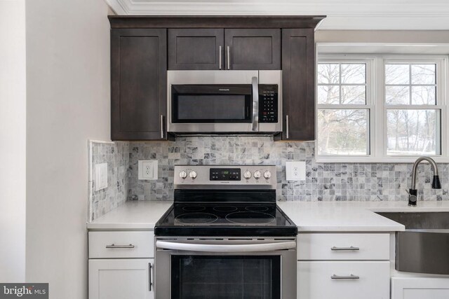 kitchen featuring stainless steel appliances, sink, backsplash, and dark brown cabinetry