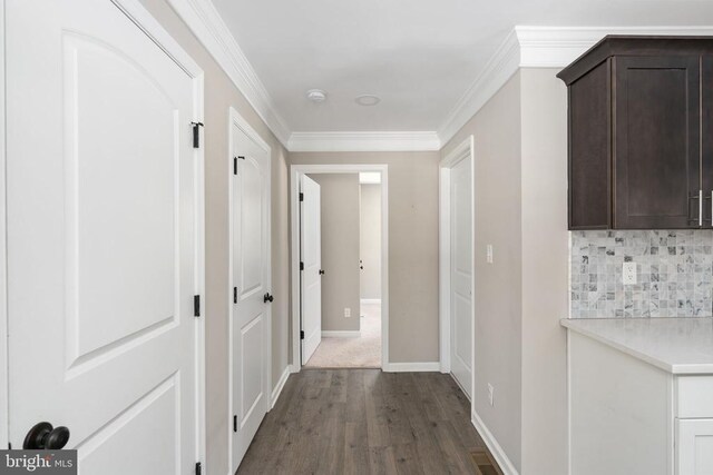 corridor with ornamental molding and dark hardwood / wood-style floors