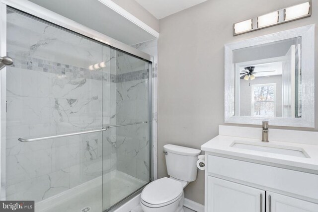 bathroom with ceiling fan, vanity, toilet, and a shower with door