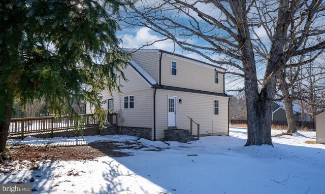 snow covered back of property with a wooden deck