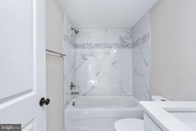 full bathroom featuring tiled shower / bath combo, vanity, and toilet