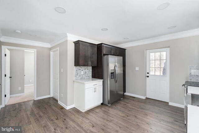 kitchen with hardwood / wood-style flooring, stainless steel refrigerator with ice dispenser, crown molding, and decorative backsplash