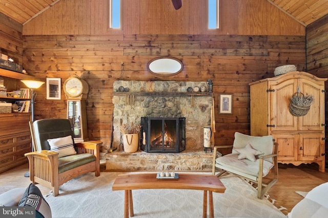 living area featuring a stone fireplace, wood finished floors, wooden walls, and wooden ceiling