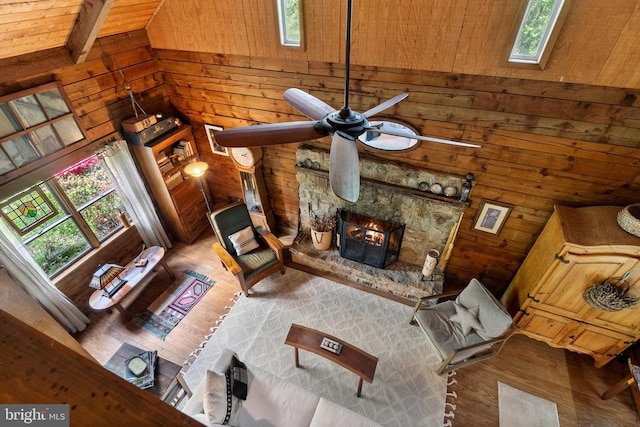living area with lofted ceiling with skylight, wood walls, ceiling fan, and wood finished floors
