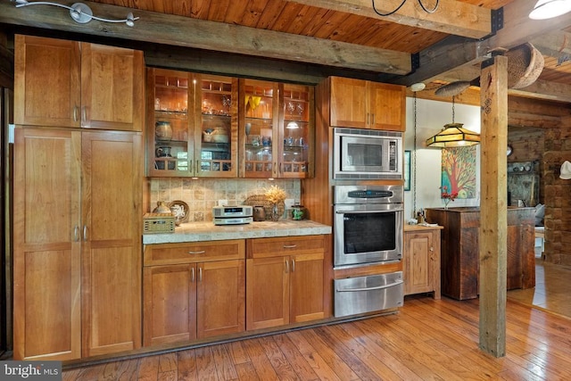 kitchen featuring light wood-style flooring, a warming drawer, beam ceiling, and stainless steel appliances